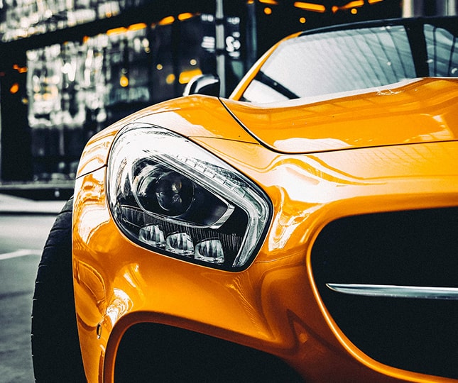 A right close up of a yellow Mercedes AMG sports car headlight on a city street