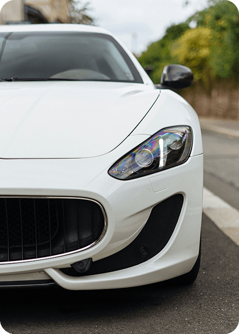 A right close up of a yellow Mercedes AMG sports car headlight on a city street